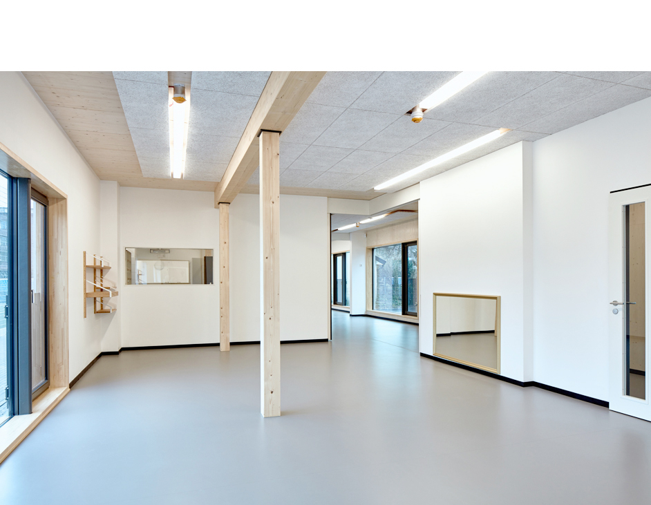 Aloys Kiefer Architekturfotografie: Querformatige Innenansicht. Neonröhren beleuchten den Raum. Holzständer in der Mitte des Bildes. Blick auf einen in die Bildtiefe führenden Flur.