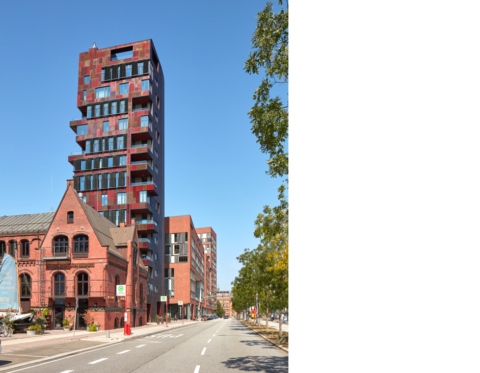 Aloys Kiefer Architekturfotografie: Hochformat Motiv. Rechts im Anschnitt ein belaubter Baum. Im Vordergrund eine Straße, die vom Betrachter wegführt. Auf der linken Seite ein altes rotes Haus mit Spitzgiebel. Dahinter ein rotes Hochhaus.
